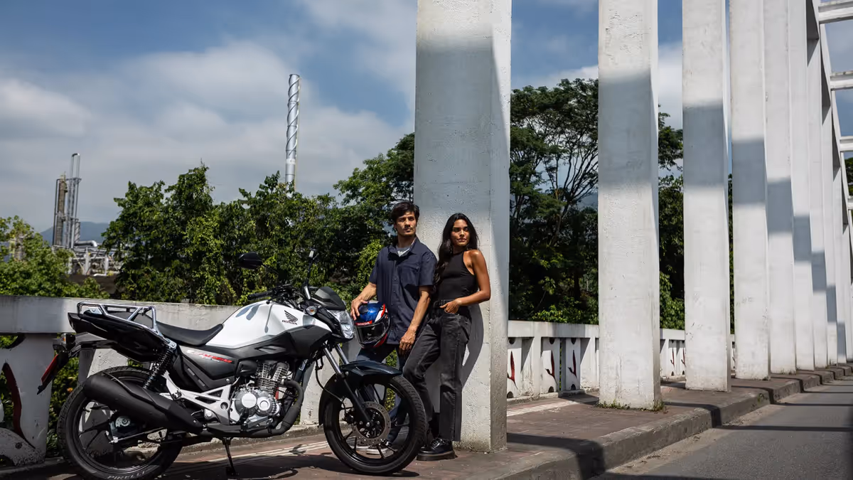 Casal olhando para o horizonte à frente da moto CG Cargo